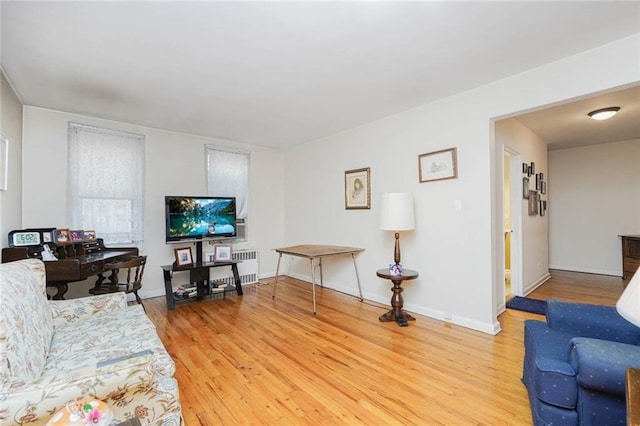living room with radiator heating unit, light wood finished floors, and baseboards