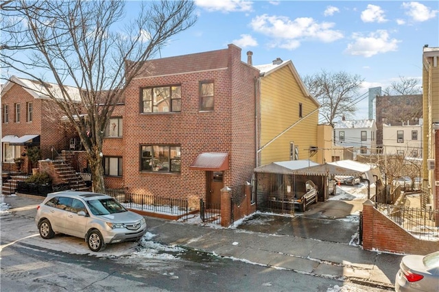 view of front of home with brick siding, fence, and stairs