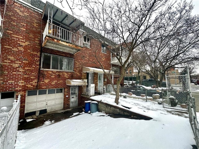 view of front of property featuring brick siding, an attached garage, fence, and a balcony