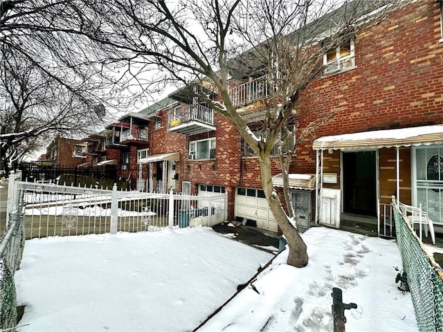 view of front of property featuring brick siding, an attached garage, and fence