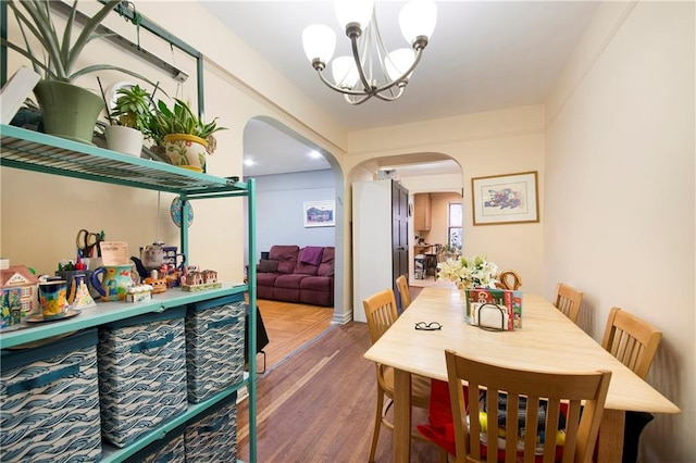 dining room featuring an inviting chandelier, parquet flooring, and arched walkways