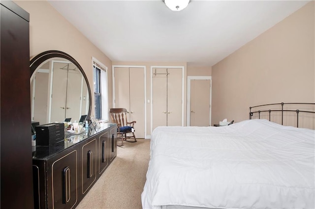 bedroom with light colored carpet and multiple closets