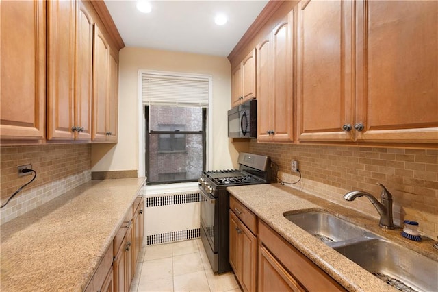 kitchen featuring radiator, black appliances, a sink, and light stone counters