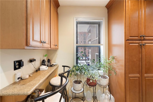 kitchen featuring brown cabinetry, a kitchen breakfast bar, and light stone counters