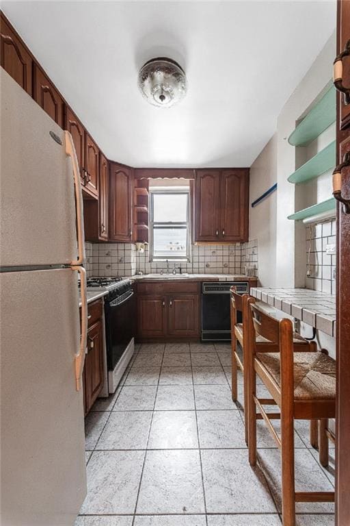 kitchen featuring tasteful backsplash, freestanding refrigerator, open shelves, black dishwasher, and range with gas stovetop