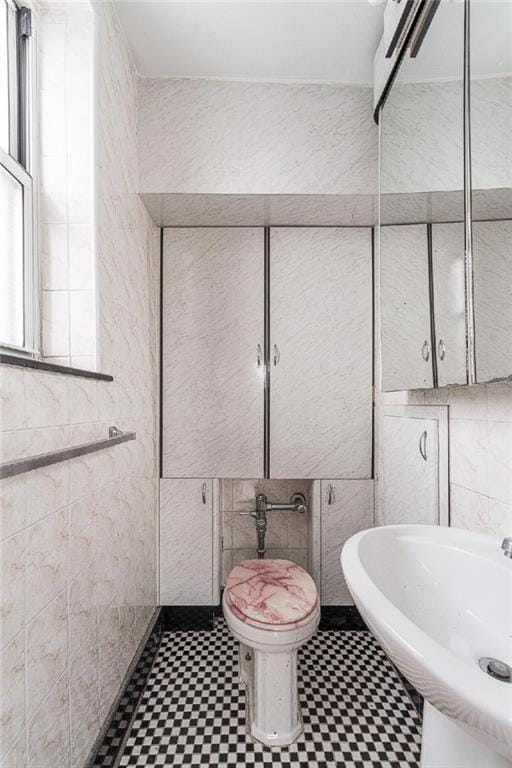 bathroom featuring tile patterned floors, a sink, toilet, and tile walls