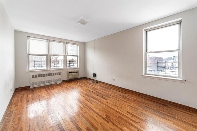 empty room with radiator, a healthy amount of sunlight, and light wood-style flooring