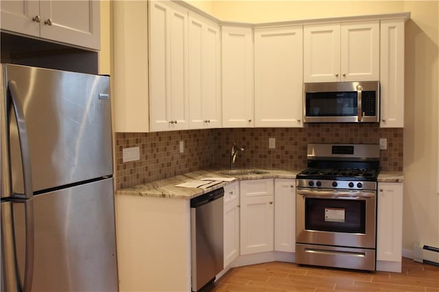 kitchen featuring sink, white cabinets, decorative backsplash, light stone counters, and stainless steel appliances