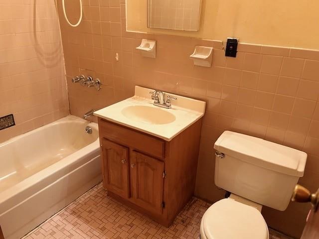 bathroom with tile walls, vanity, toilet, and shower / bath combo