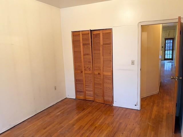 unfurnished bedroom with a closet, baseboards, and wood finished floors