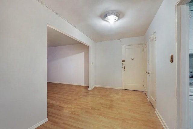 corridor with light wood-type flooring and baseboards