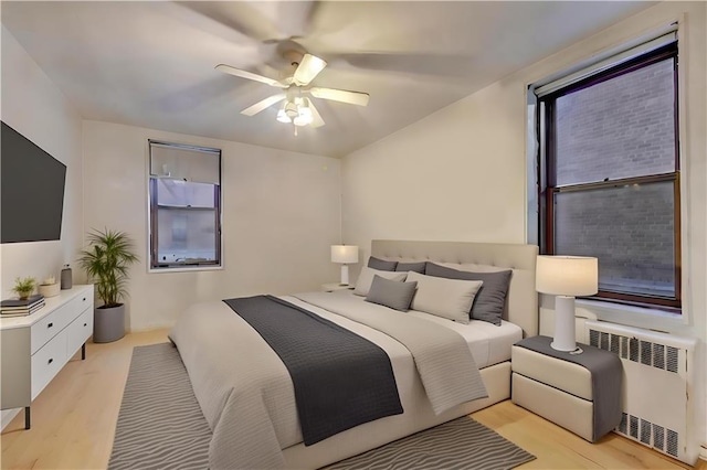 bedroom with light wood-style floors, radiator, and ceiling fan