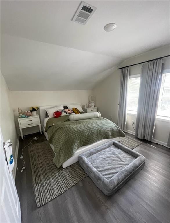 bedroom featuring visible vents, baseboards, wood finished floors, and vaulted ceiling