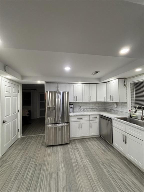 kitchen featuring a sink, white cabinetry, stainless steel appliances, light countertops, and decorative backsplash