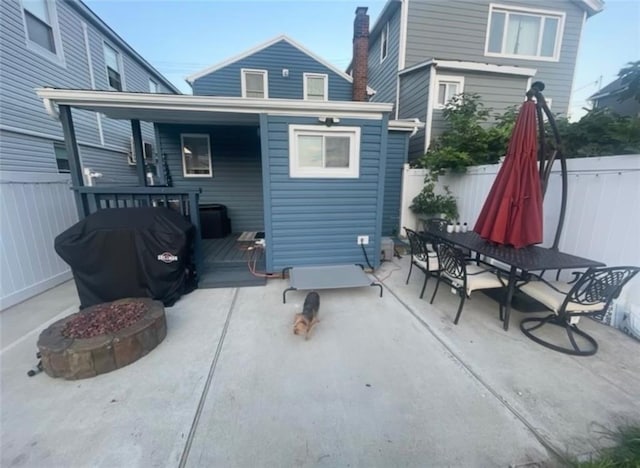 rear view of property featuring a patio area, outdoor dining space, an outdoor fire pit, and a fenced backyard