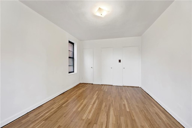 spare room featuring baseboards and light wood finished floors