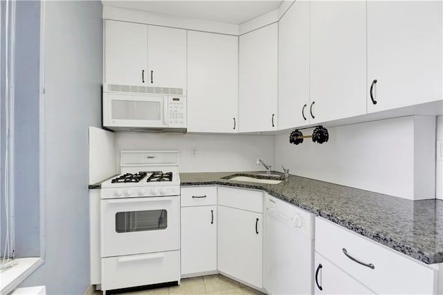 kitchen featuring white appliances, white cabinets, and dark stone countertops