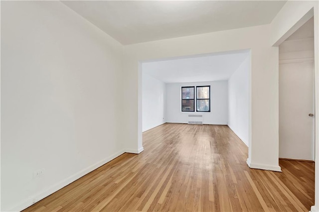 spare room featuring baseboards and light wood-type flooring