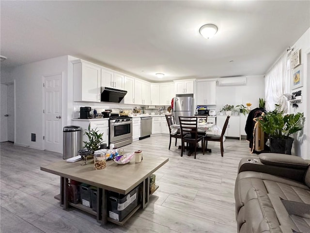 living area with light wood-style flooring and an AC wall unit