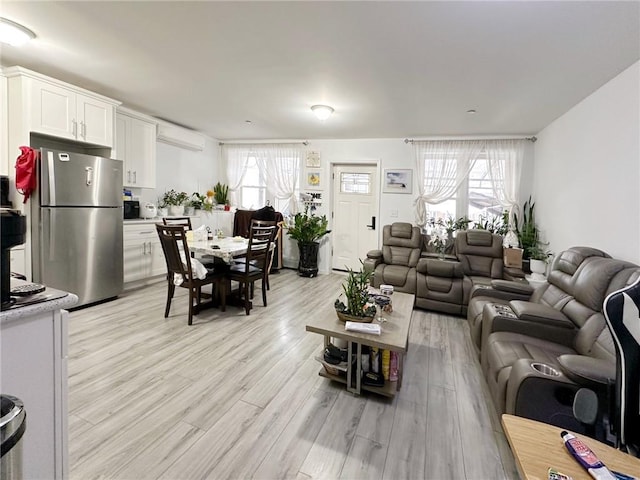 living area featuring an AC wall unit and light wood-style floors