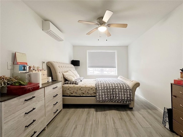 bedroom with light wood-style floors, an AC wall unit, baseboards, and a ceiling fan