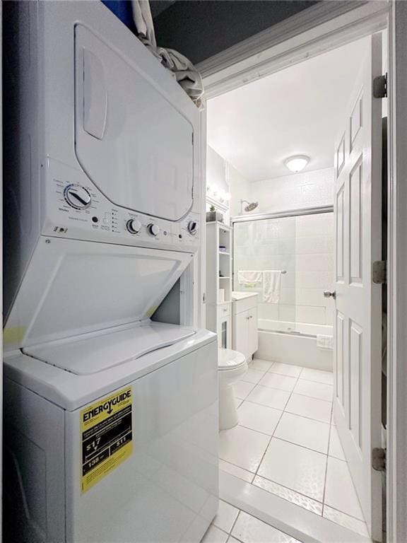 washroom featuring stacked washer / dryer, light tile patterned flooring, and laundry area