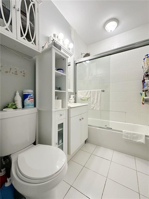 full bath with combined bath / shower with glass door, vanity, toilet, and tile patterned floors