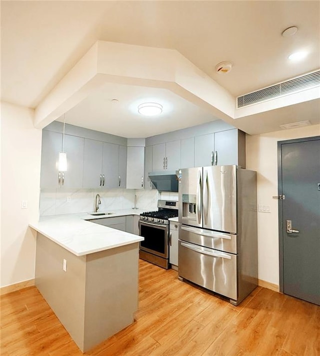 kitchen with kitchen peninsula, stainless steel appliances, light wood-type flooring, and decorative light fixtures