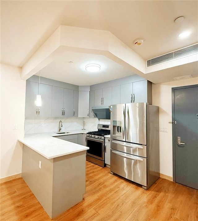 42-22 Crescent St Unit 2C, Long Island City, NY 11101 - kitchen featuring stainless steel appliances, a peninsula, under cabinet range hood, decorative backsplash, and light wood-style floors