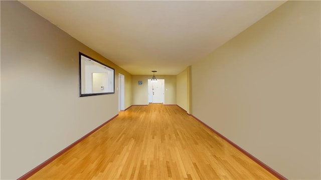 hallway with an inviting chandelier and light hardwood / wood-style floors