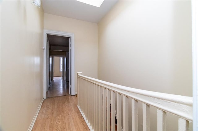 hall featuring light wood-type flooring and a skylight