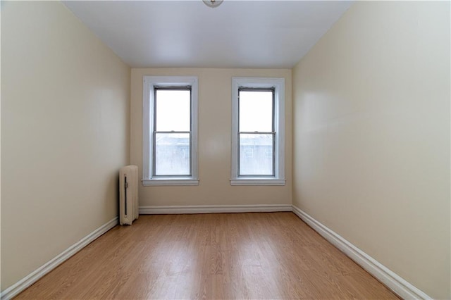 unfurnished room with radiator and light wood-type flooring