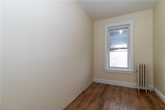 unfurnished room featuring radiator and dark wood-type flooring