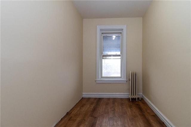 empty room with radiator heating unit and dark hardwood / wood-style floors