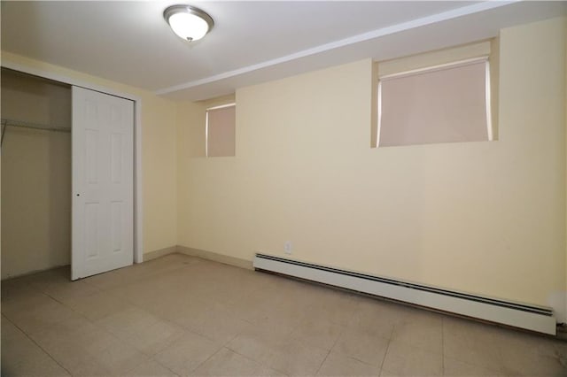 unfurnished bedroom with a baseboard heating unit and a closet