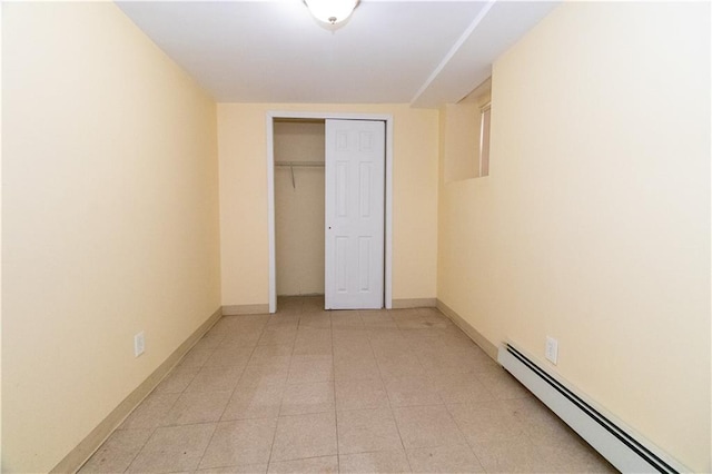 unfurnished bedroom featuring a baseboard heating unit, light tile patterned floors, and a closet