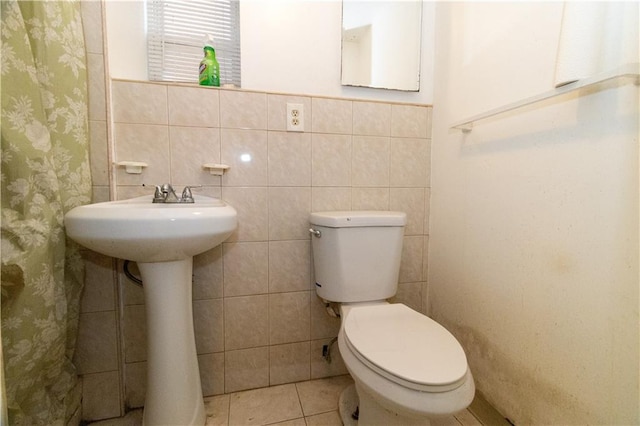 bathroom with tile walls, tile patterned floors, and toilet