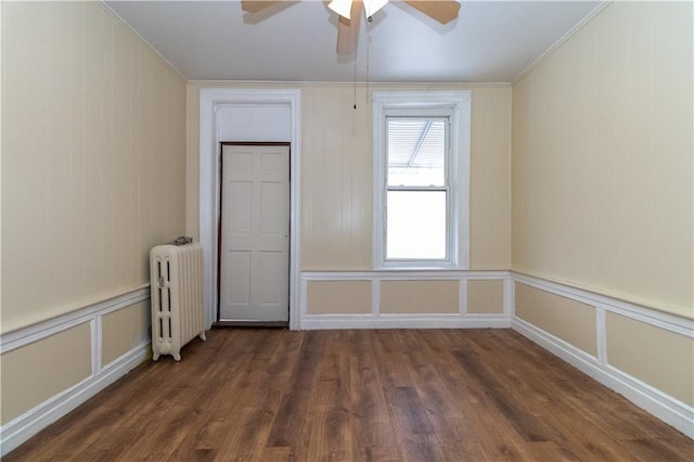 empty room with ornamental molding, dark hardwood / wood-style floors, radiator heating unit, and ceiling fan