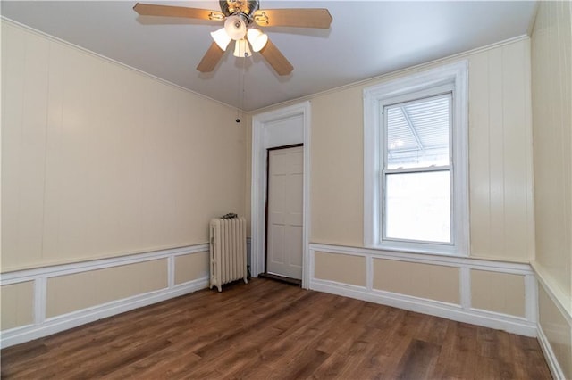 empty room with ceiling fan, dark hardwood / wood-style flooring, and radiator