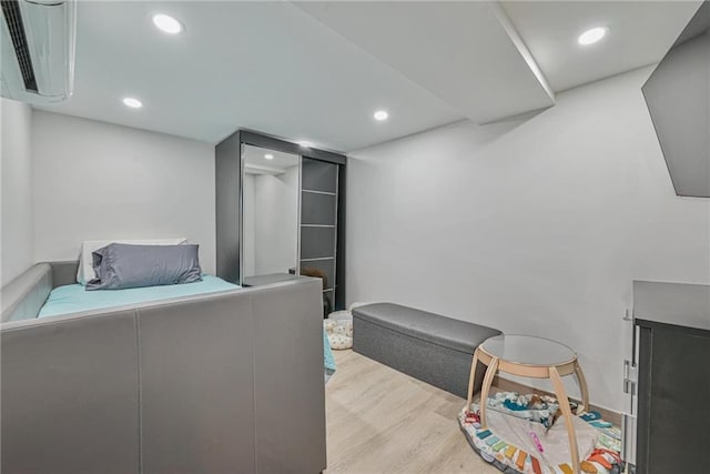 bedroom featuring light hardwood / wood-style floors and a wall mounted AC