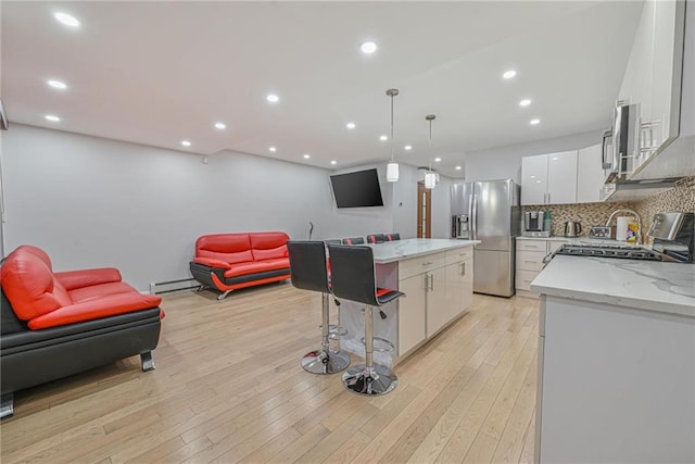 kitchen with white cabinetry, stainless steel fridge, a kitchen island, pendant lighting, and a baseboard heating unit