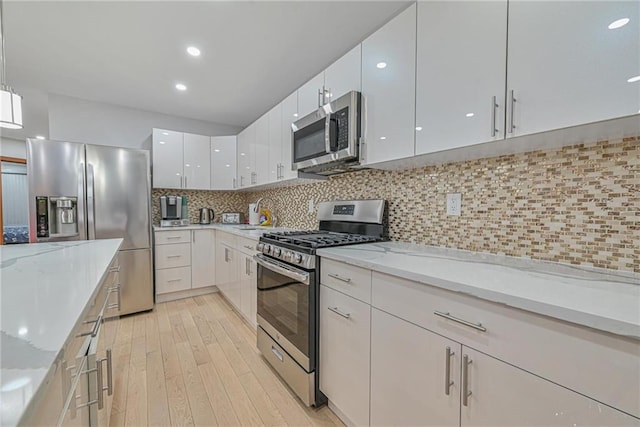 kitchen featuring white cabinetry, appliances with stainless steel finishes, hanging light fixtures, and light stone counters