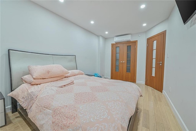 bedroom featuring light hardwood / wood-style floors and an AC wall unit