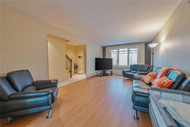 living room with a baseboard heating unit, radiator, and light wood-type flooring