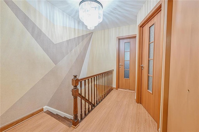 corridor featuring a notable chandelier and light hardwood / wood-style flooring