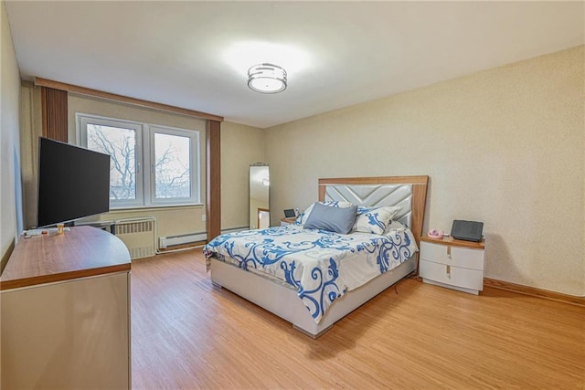 bedroom with a baseboard heating unit, light hardwood / wood-style flooring, and radiator heating unit