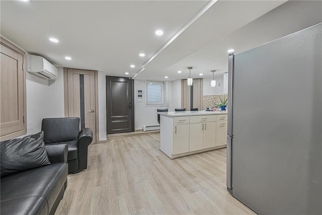 kitchen featuring hanging light fixtures, light wood-type flooring, stainless steel refrigerator, a baseboard radiator, and a wall unit AC