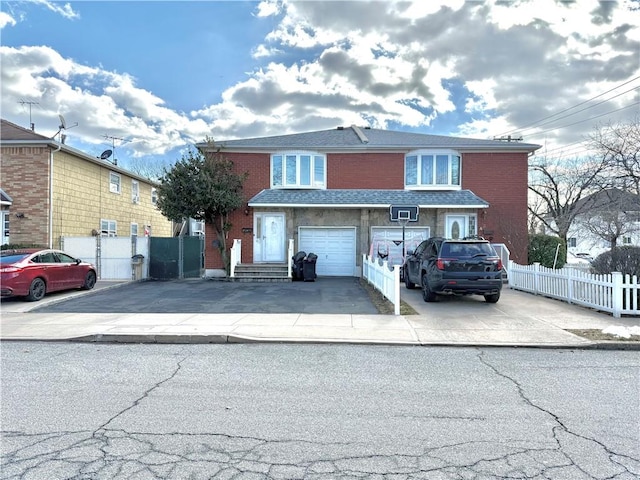 view of front of house featuring driveway, fence, and brick siding