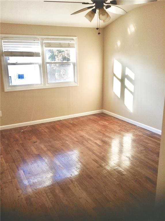 spare room featuring a ceiling fan, baseboards, and hardwood / wood-style floors