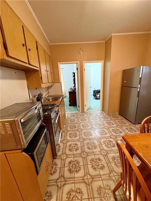 kitchen with crown molding, appliances with stainless steel finishes, and sink